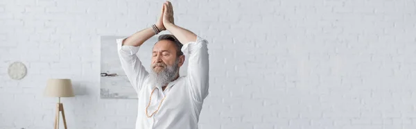 Homme barbu senior en chemise blanche méditant avec les bras levés et les mains priantes, bannière — Photo de stock