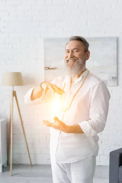 Happy master guru smiling at camera near shining chakra — Stock Photo