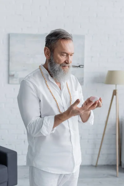 Bearded spiritual coach in white shirt and beads meditating with selenite crystal — Stock Photo