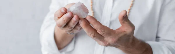 Cropped view of guru master holding selenite crystal isolated on grey, banner — Stock Photo