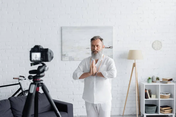 Bearded master guru meditating with praying hands in front of digital camera at home — Stock Photo