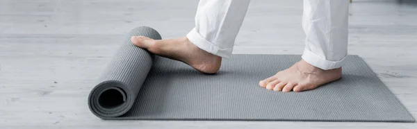 Cropped view of master guru unrolling yoga mat, banner — Stock Photo