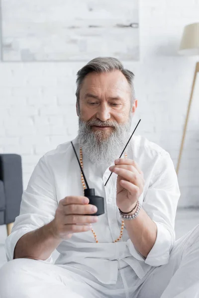 Bearded healing master holding diffuser with aroma sticks at home — Stock Photo