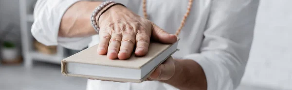 Vista ritagliata dell'uomo guru in braccialetti di perline meditando con libro, banner — Foto stock