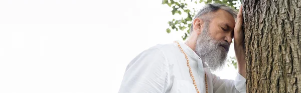 Low angle view of bearded guru man with closed eyes meditating near tree outdoors, banner — Stock Photo