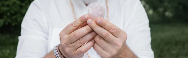 Cropped view of blurred guru man holding selenite crystal outdoors, banner — Stock Photo