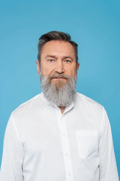 Wise senior man with grey beard looking at camera isolated on blue — Stock Photo