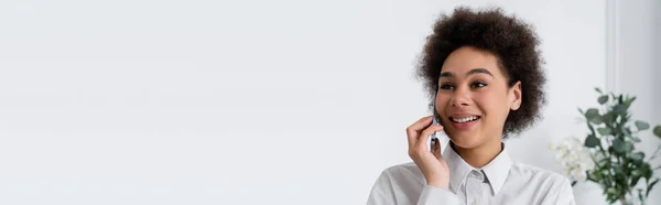Mujer afroamericana feliz hablando en el teléfono inteligente en casa, bandera - foto de stock