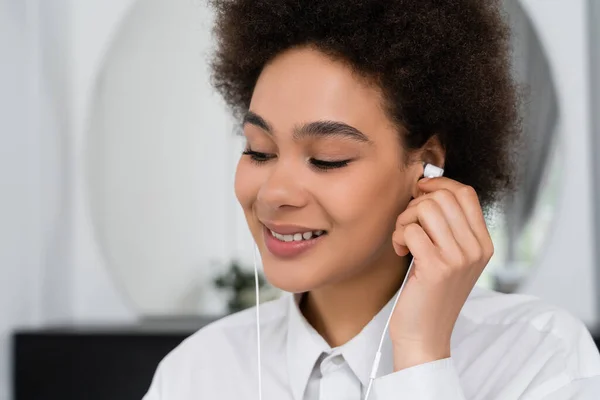 Happy african american woman listening music in wired earphones — Stock Photo