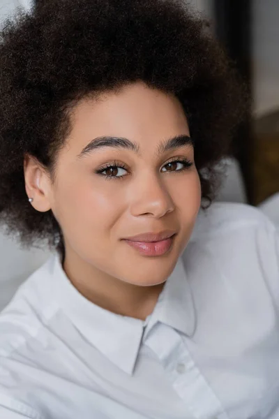 High angle view of smiling and curly african american woman in white shirt with collar — Stock Photo