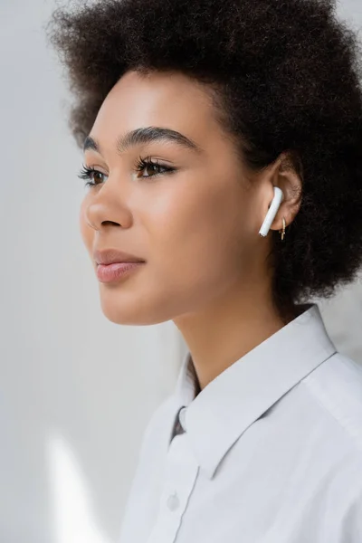 Portrait of curly african american woman listening music in wireless earphone — Stock Photo