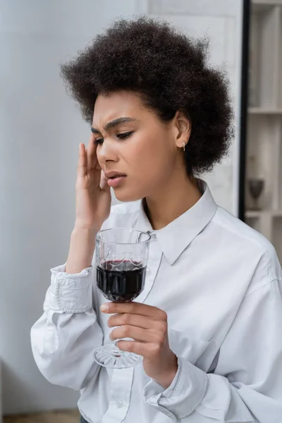 Femme afro-américaine frustrée tenant un verre de vin rouge — Photo de stock