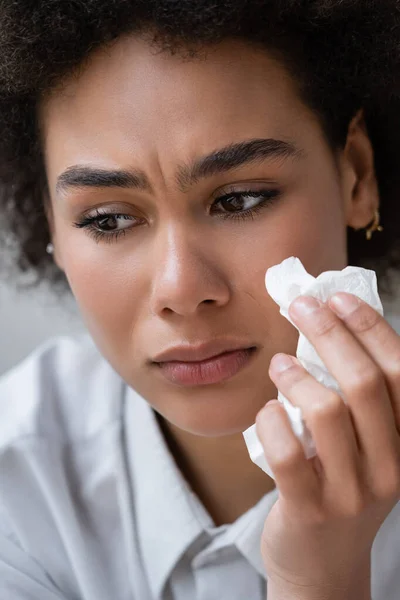 Close up of african american woman in white shirt crying and holding napkin — Stock Photo