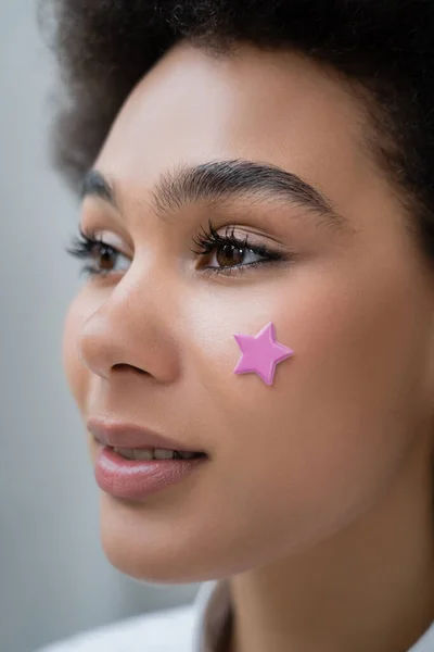 Portrait of african american woman with decorative purple star on cheek — Stock Photo