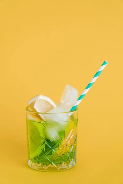 Cítricos cortados en rodajas en vaso con bebida mojito y paja sobre amarillo - foto de stock