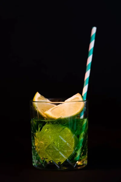 Sliced citrus fruits in glass with alcohol drink and straw isolated on black — Fotografia de Stock