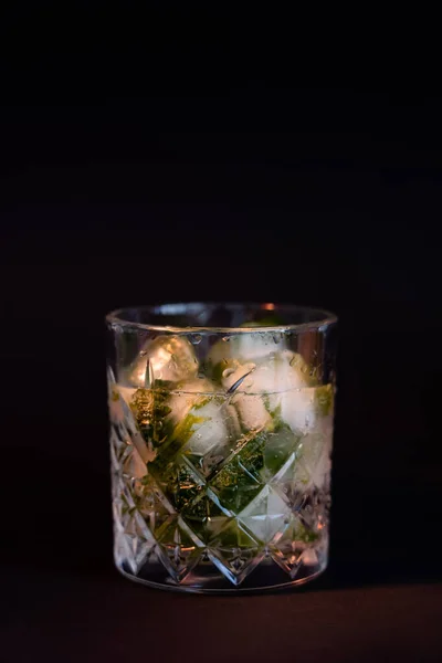 Cool faceted glass with rum and ice cubes isolated on black — Fotografia de Stock