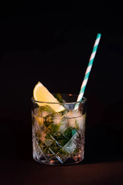 Cool faceted glass with mojito and ice cubes isolated on black — Stock Photo