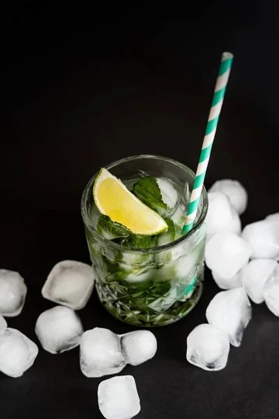 High angle view of cool faceted glass with mojito near ice cubes on black - foto de stock