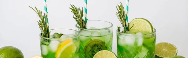 Faceted glasses with cold green cocktail, straws and fruits isolated on white, banner — Stock Photo