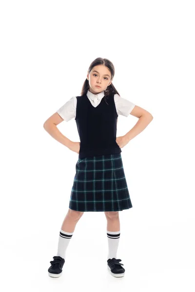 Serious schoolgirl standing in akimbo pose on white background — Stock Photo