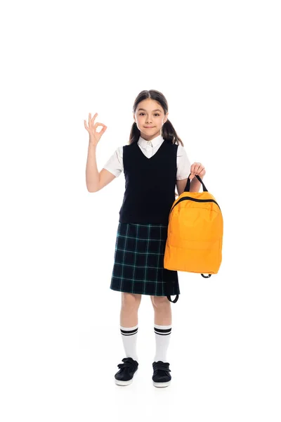 Full length of pupil showing ok gesture and holding backpack on white background — Stock Photo