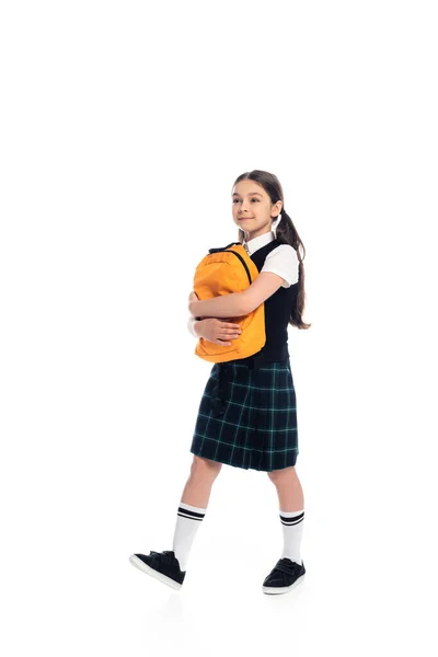 Full length of schoolgirl holding backpack and walking on white background — Stock Photo