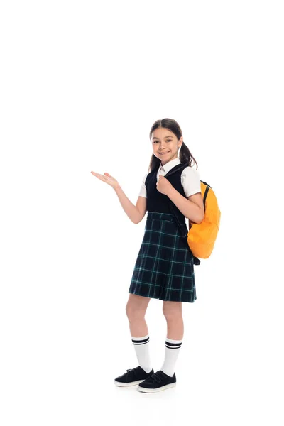 Volle Länge des lächelnden Schulmädchens mit Rucksack, der mit der Hand auf weißem Hintergrund zeigt — Stockfoto