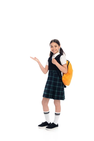 Comprimento total de colegial sorridente com mochila apontando com a mão no fundo branco — Fotografia de Stock