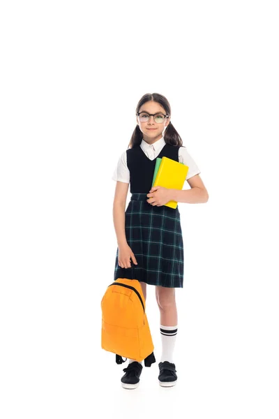 Toute la longueur de l'écolier en lunettes tenant des livres et un sac à dos sur fond blanc — Photo de stock