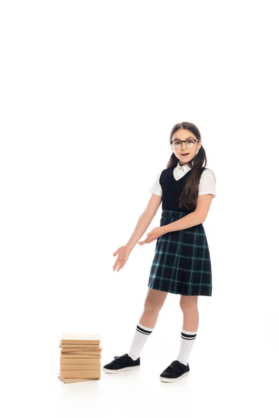 Excited schoolgirl in eyeglasses pointing at books on white background — Stock Photo