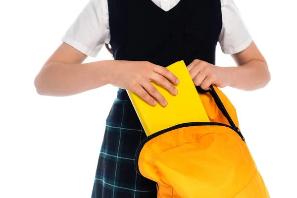 Vista recortada de colegiala poniendo libro en la mochila aislado en blanco - foto de stock