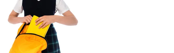 Cropped view of schoolchild putting book in backpack isolated on white, banner — Stock Photo