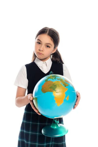 Серйозна школярка тримає глобус і дивиться на камеру ізольовано на білому — стокове фото