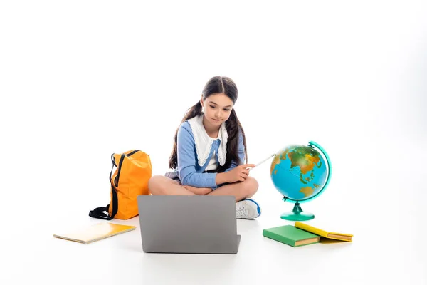 Écolier pointant vers le gant près de l'ordinateur portable et des livres sur fond blanc — Photo de stock