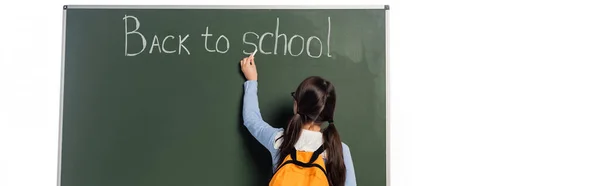 Visão traseira do aluno com mochila escrevendo de volta para a escola lettering no quadro isolado em branco, banner — Fotografia de Stock