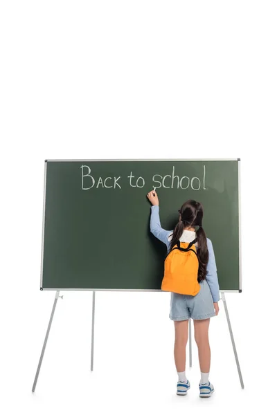 Vue arrière de l'écolier écrivant de retour à l'école lettrage sur tableau noir sur fond blanc — Photo de stock