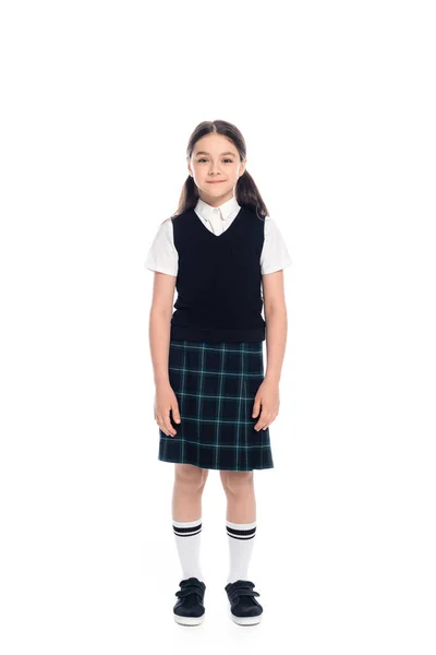 Full length of smiling schoolkid in plaid skirt standing on white background — Stock Photo