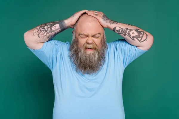 Upset bearded man with overweight touching bald head isolated on green — Stock Photo