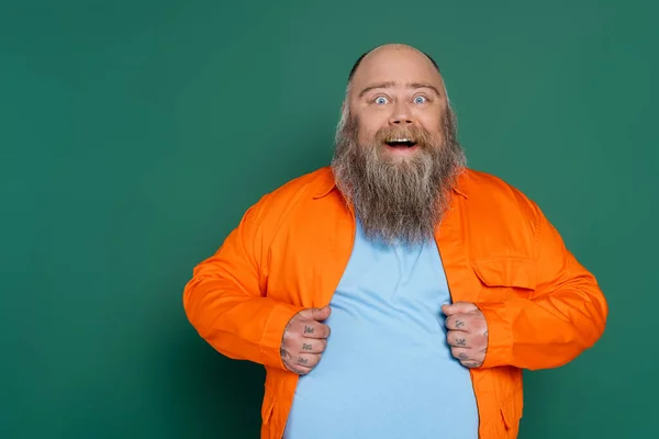 Erstaunt übergewichtiger Mann mit Bart blickt in Kamera isoliert auf Grün — Stockfoto