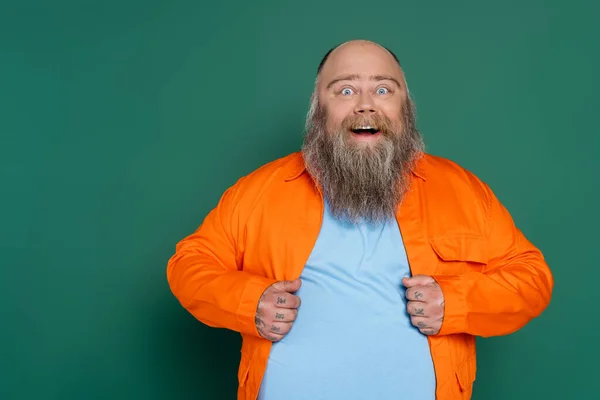 Surpreso homem com excesso de peso com barba olhando para câmera isolada no verde — Fotografia de Stock