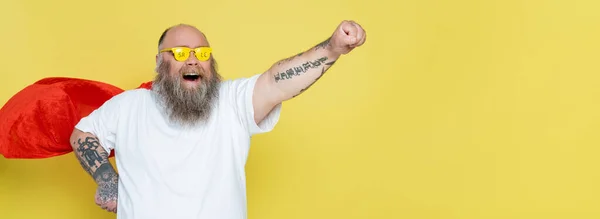 Excited overweight man in superhero cloak and glasses with sale lettering isolated on yellow, banner — Stock Photo