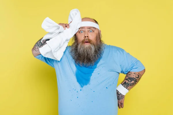 Verschwitzt und müde plus Größe Sportler wischen Kopf mit Handtuch isoliert auf gelb — Stockfoto