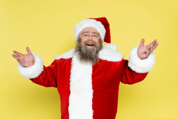 Joyful and chubby santa claus showing greeting gesture isolated on yellow — Fotografia de Stock