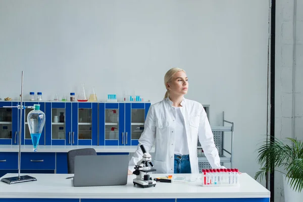 Scientist standing near laptop and microscope in laboratory — Stock Photo
