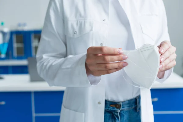 Cropped view of scientist holding medical mask in lab — Stock Photo