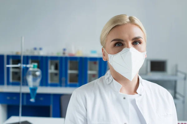 Блондинка в защитной маске смотрит на камеру в лаборатории — стоковое фото