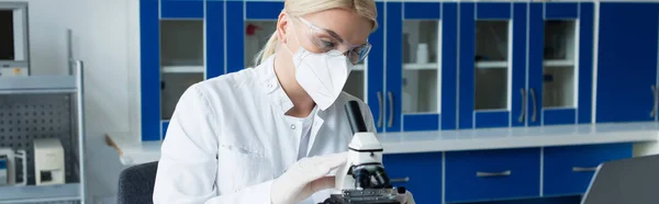 Scientist in goggles and protective mask using microscope in lab, banner — Stockfoto