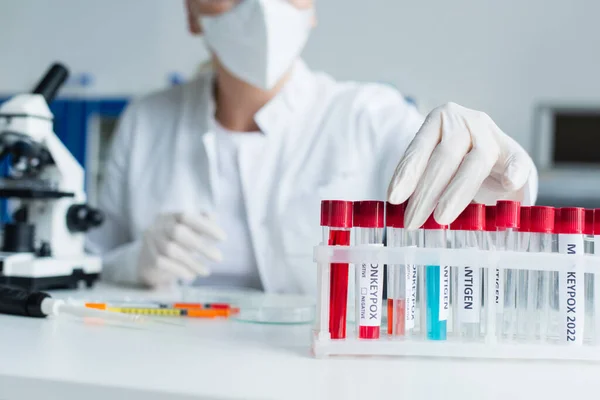 Cropped view of blurred scientist taking test tube with monkeypox lettering in lab — Stock Photo