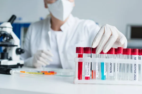 Cropped view of blurred scientist taking test tube with monkeypox lettering in lab — Photo de stock